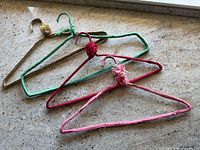 Three crochet-covered wire hangers in different colors