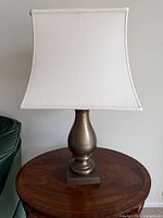 Full view of brass lamp with shade on side table