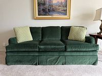 Front view of emerald green velvet Ethan Allen sofa with two throw pillows