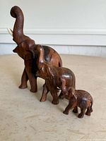 Side view of three wooden elephant sculptures lined up by size