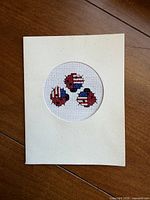 Front of folded card displaying circular cut-out with cross-stitch ladybug design