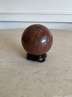 Front view of red jasper sphere on black stand