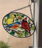 Full view of oval stained glass sun catcher hanging in window