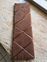 Full view of brown memo board showing ribbon lattice and buttons