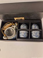 Boxed set showing teapot, four cups, wooden scoop