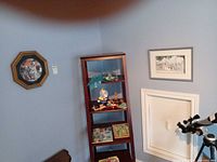 Shelf with puzzles, vintage toys, clown figurine; framed Dalmatian plate and seascape painting visible