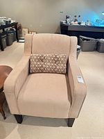 Front view of beige armchair with lumbar pillow