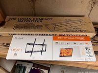 Both boxed items: Logan Compact Mat Cutter and Brateck TV wall mount