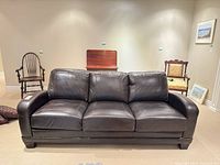 Front view of dark brown leather three-seat sofa showing overall design and condition