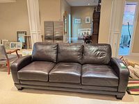 Front view of brown leather three-cushion sofa