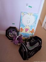 Group shot of all four items: canvas painting, framed plate, flower basket, duffel