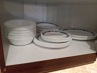 Stack of white bowls and stacks of blue-rim plates inside cupboard