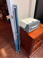 Projector unit beside folded Da-Lite screen tripod