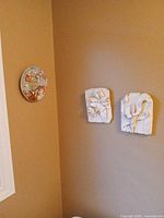 Overall view showing decorative plate and two white floral relief plaques mounted on wall