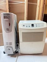Front view of DeLonghi radiator beside Kenmore dehumidifier