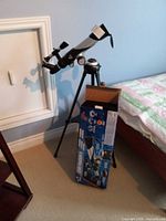 Telescope mounted on tripod beside original box and carrying case