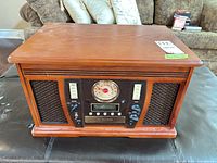Full front view of media center showing wood cabinet, speaker grilles, control panel, analog dial, CD recorder slot