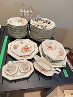 Overall set showing stacked plates, bowls, flatware, gravy boat, and shakers