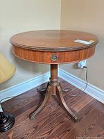 Full view of round pedestal side table with drawer and legs