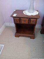 Front view of nightstand showing drawer, shelf, knobs, finish