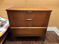 front view of three-drawer walnut dresser on tapered legs