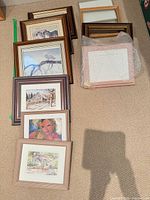 Group of framed prints stacked and laid out on carpet