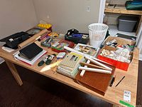 overview of entire lot on tabletop showing notebooks, toolbox, portfolios, seashells, extension cords, tube lights, binders and waste basket