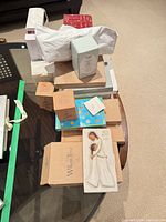 Stack of boxed figurines, flatware and gifts on table