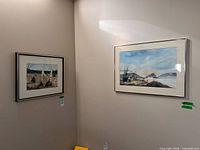 Both framed paintings on wall: birch woodland left, coastal scene right
