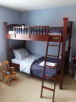 Full view of assembled twin-over-twin bunk bed with ladder and bedding