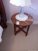 Full view of round solid wood side table with lamp on top