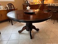 Full view of round wood dining table with pedestal base in kitchen setting