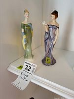 Both Royal Doulton figurines on shelf with lot tag visible