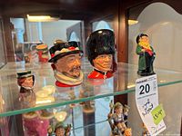 Four Royal Doulton pieces on glass shelf