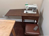 Sewing machine mounted in cabinet with bench and foot pedal visible