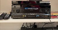 Front view of Sony receiver stacked with Samsung Blu-ray player, remotes visible