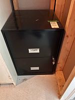 Front view of black two-drawer SteelWorks lateral cabinet showing drawers and key in lock