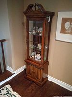 Full view of curio cabinet showing glass door, lower storage, wood finish