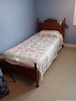 Twin wooden bed with quilt in room