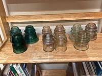 Shelf view showing all nine glass insulators in assorted colors and shapes