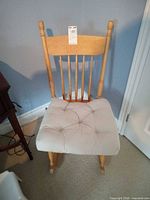 Front view of light wood spindle-back rocking chair with beige tufted cushion