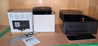 Both boxed Apple TV units with their remotes displayed