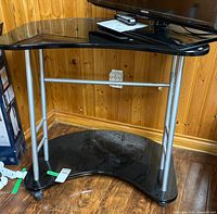 Full view of stand showing black glass top, silver frame, lower shelf and casters