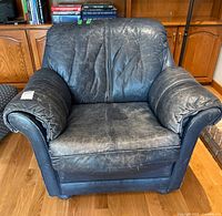 Front view of blue leather armchair showing overall design and wear