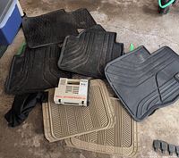 Assortment of black and tan BMW rubber mats with air compressor