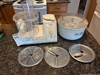 Full set showing motor base, clear processor bowl, white mixing bowl with lid, three discs