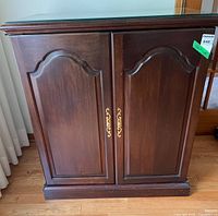 Front view of cabinet closed showing brass handles and glass top