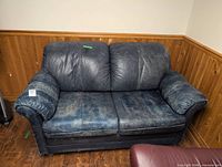 Front view of blue leather loveseat showing overall form and wear