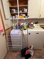 overview of drying rack, brooms, dustpans beside washer