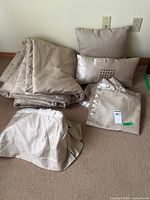 All pieces of bedding set laid out: comforter, shams, bed skirt, decorative pillows